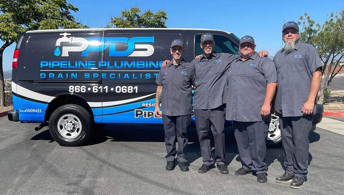 plumbers in front of a plumbing van